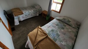 Een kamer met twee bedden, een raam en een deur.