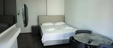 Ein Hotelzimmer mit einem Bett, einem Schreibtisch, einem Stuhl, einem Spiegel und einer Wandleuchte.