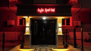 A entrada de um hotel com um letreiro de neon, um portão e um padrão de piso em azulejos.