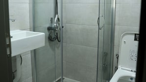 Um banheiro moderno com chuveiro em box de vidro, pia branca e vaso sanitário.