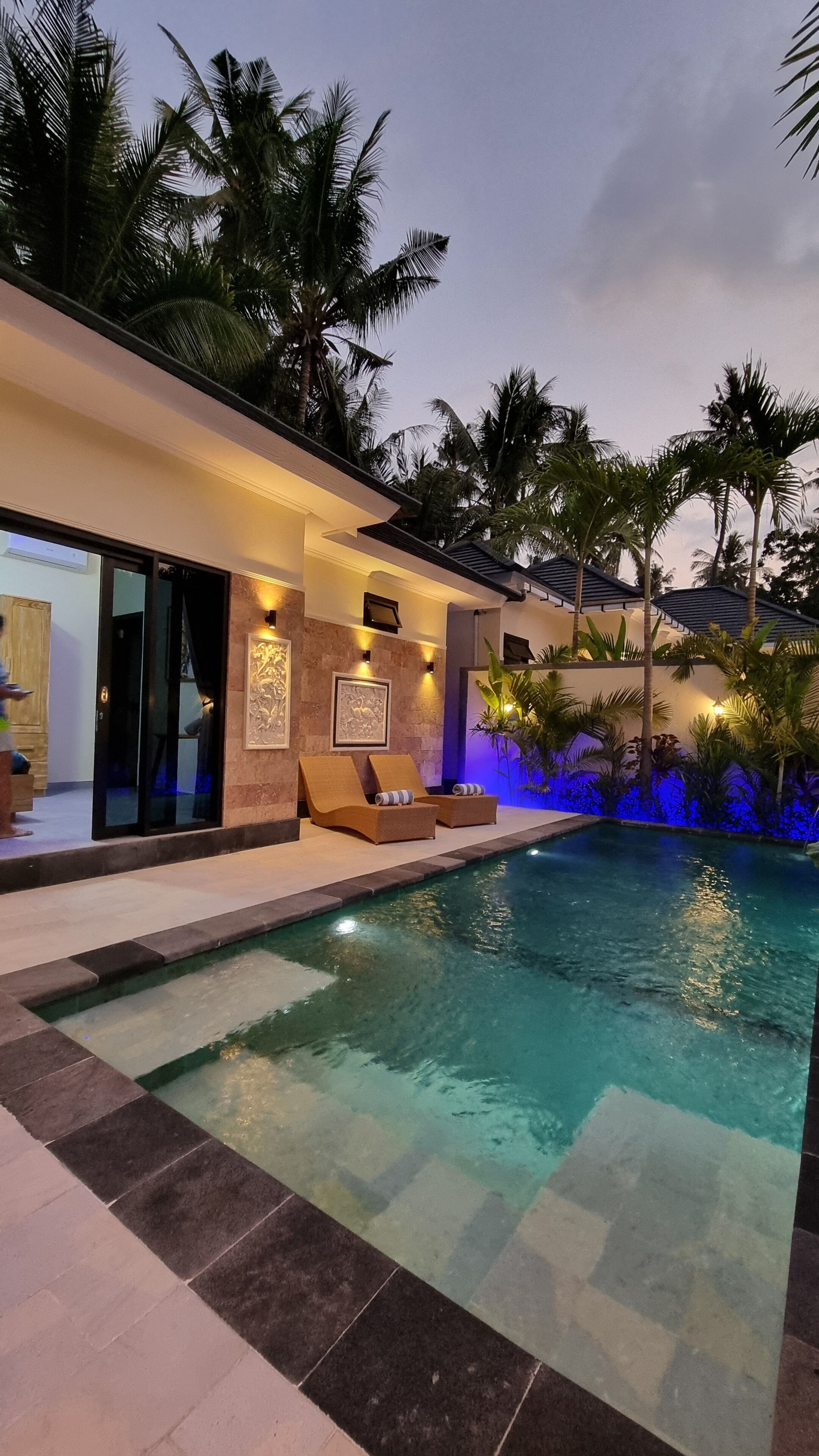 A swimming pool with lounge chairs and a view of palm trees.