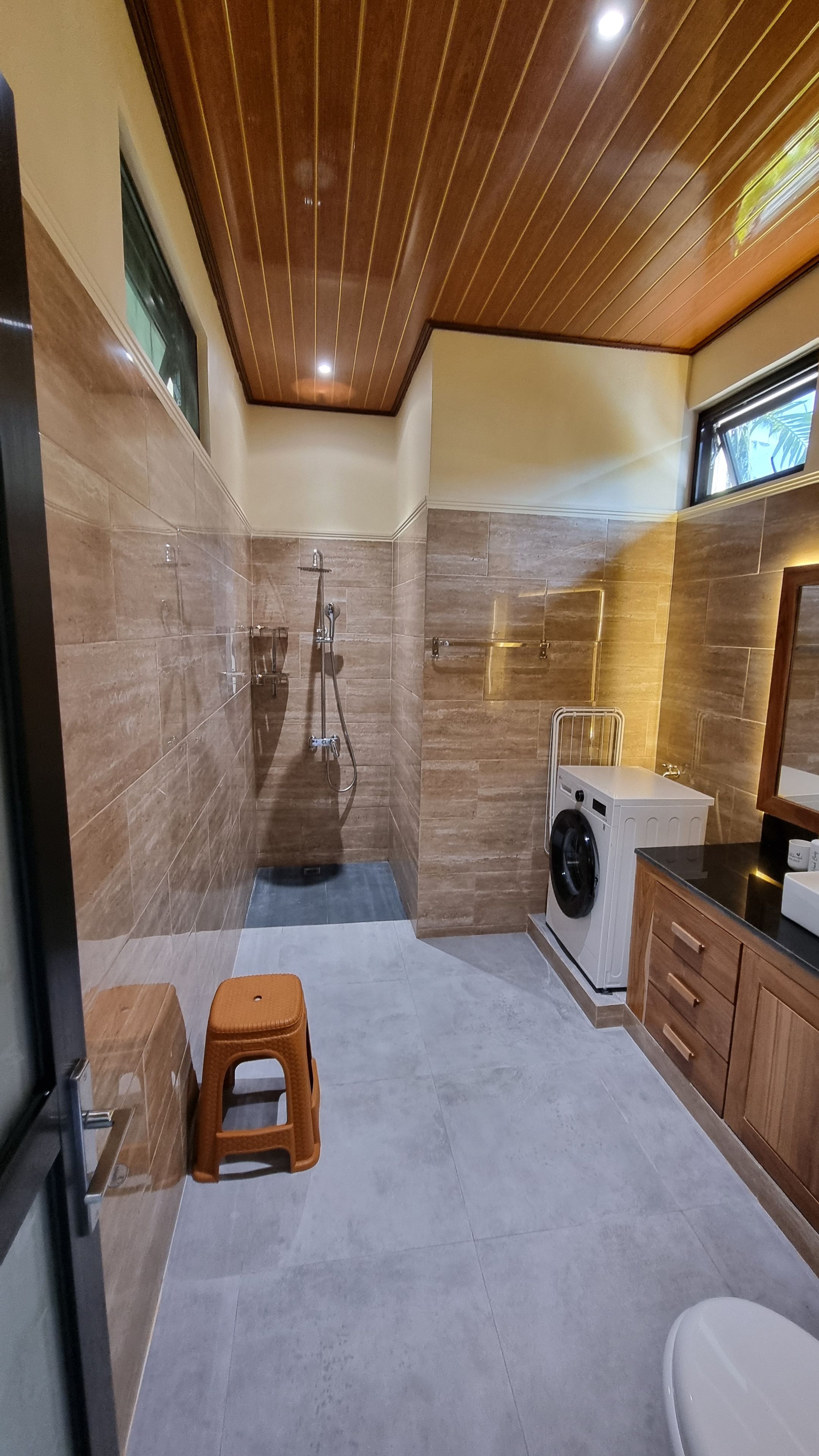 A modern bathroom with a shower, toilet, and washing machine.