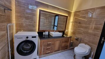Un baño moderno con lavadora, lavamanos e inodoro.