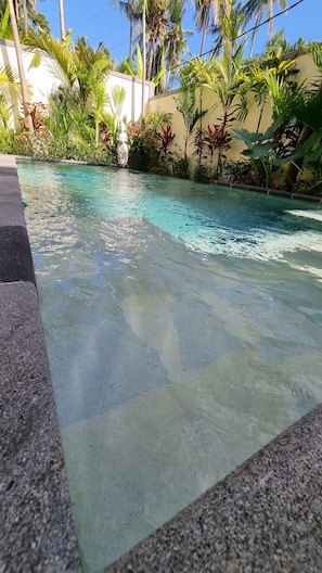 A clear pool with a stone border, surrounded by tropical plants and a statue. - "Romantic Lovina Sanctuary - Private Tropical Escape" (Buleleng)