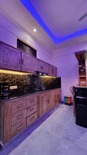 A kitchen with wooden cabinets, a black marble countertop, and a built-in stove. - Villa Kupu-Kupu 2A – Romantic Lovina Sanctuary (Buleleng)