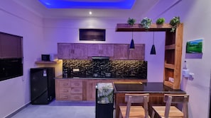 A compact kitchen with wooden cabinets, a black countertop, and a dining area with a table and chairs. - "Romantic Lovina Sanctuary - Private Tropical Escape" (Buleleng)