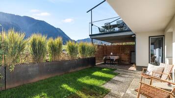 Um pátio moderno ao ar livre com área de refeições, gramado e vista para montanhas.