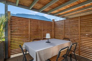 An outdoor patio with a table and chairs, a lamp, and a wooden fence.