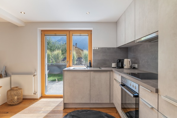 A modern kitchen with a built-in oven, a sink, and a stove. There is a window with a view of a mountain landscape.