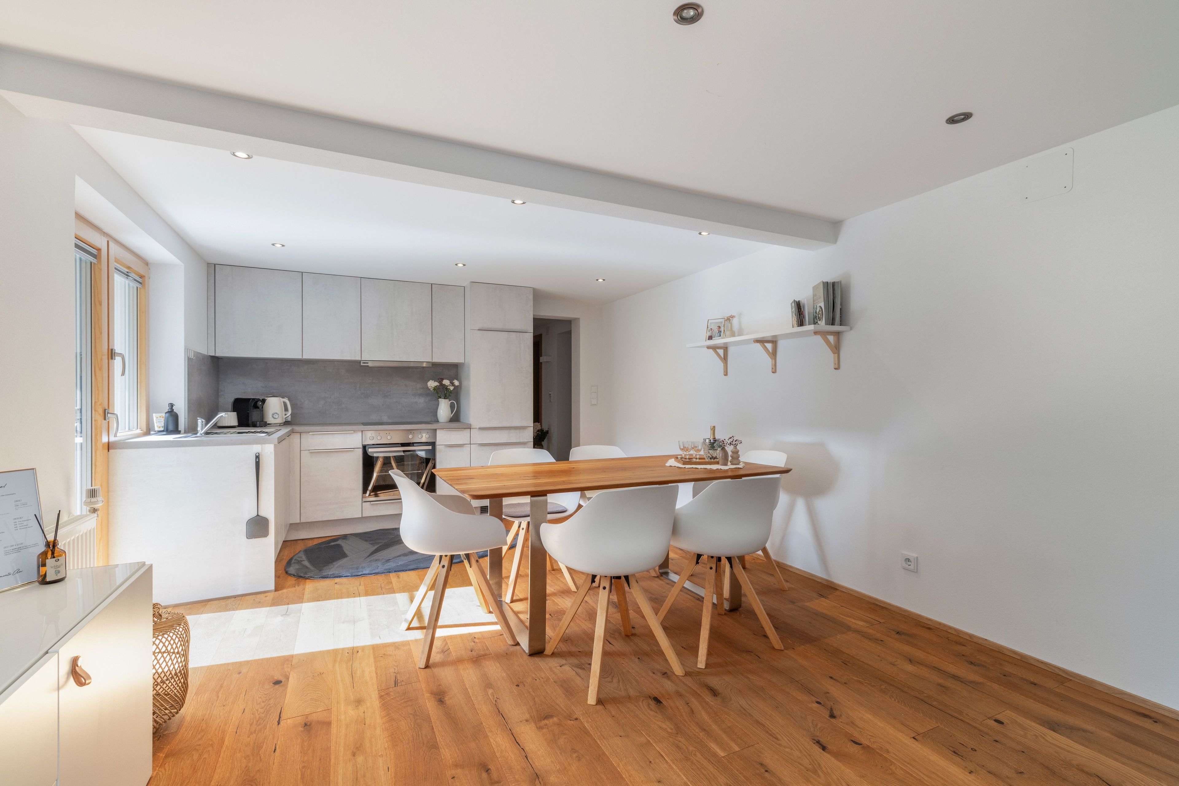 Una cucina moderna con mobili bianchi, un tavolo da pranzo in legno e un forno a incasso.