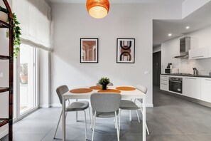 A modern dining area with a white table, grey chairs, and a hanging light fixture. - FaMa | Quiet&Bright 2-Bedroom Apartment (Roma)