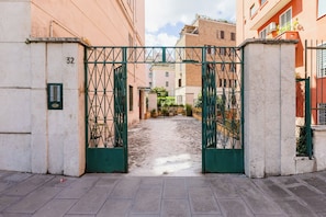 A gated entrance to a residential area with a paved pathway leading into a narrow street. - FaMa | Quiet&Bright 2-Bedroom Apartment (Roma)