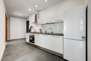A modern kitchen with white cabinetry, a built-in oven, a stainless steel range hood, and a refrigerator. - FaMa | Quiet&Bright 2-Bedroom Apartment (Roma)