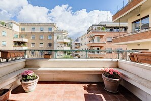 A balcony with terracotta tiles, potted plants, and a view of neighboring buildings. - FaMa | Quiet&Bright 2-Bedroom Apartment (Roma)