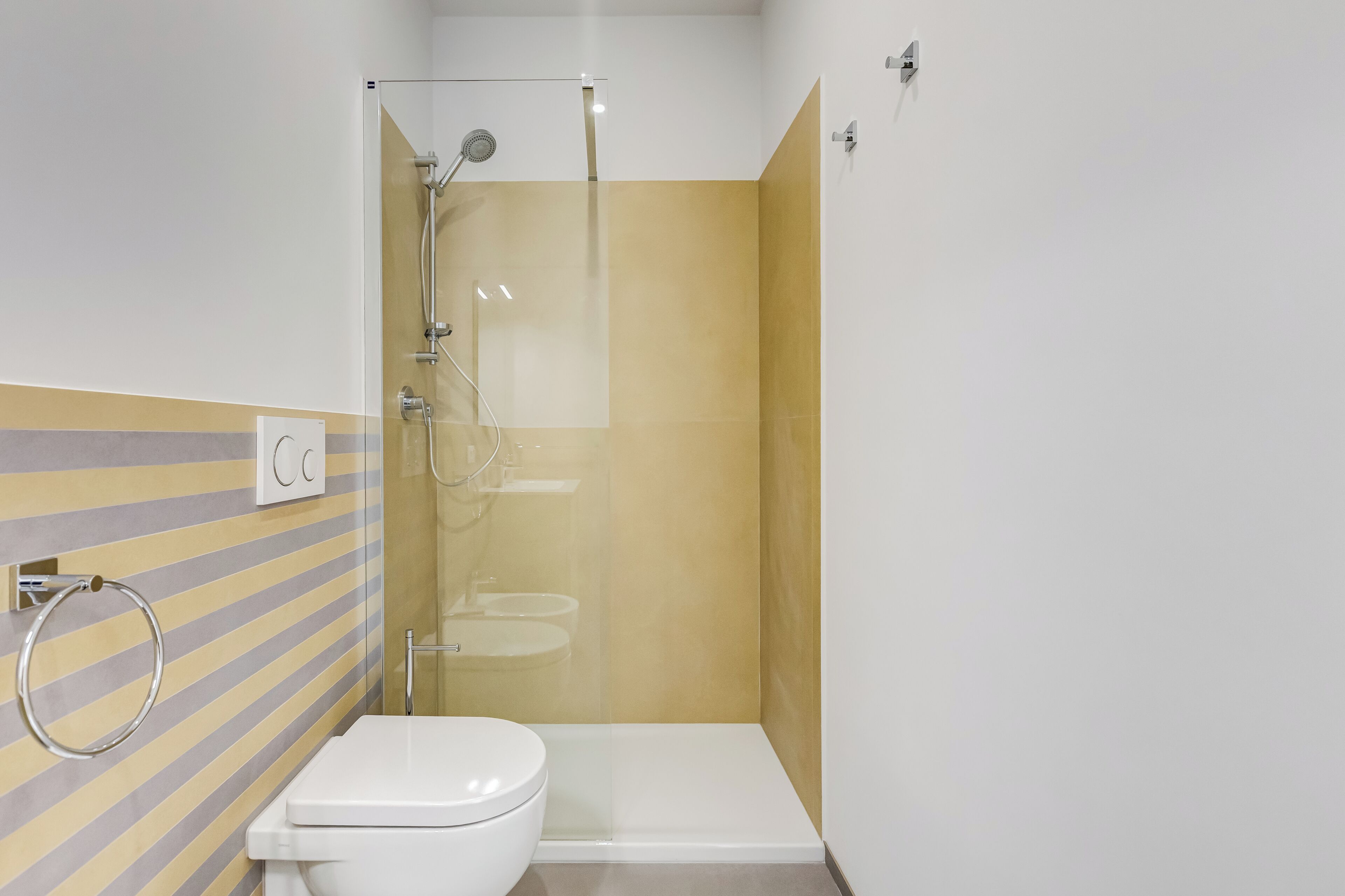 Een badkamer met douche, toilet en handdoekhouder.