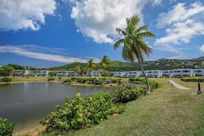 A resort with a lake, palm trees, and a building with a flat roof. - Steps to Sapphire's Sandy Beach - D12 Crystal Cove - Sapphire Bay West (St Thomas)