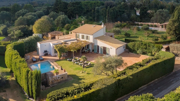 Una villa con piscina, rodeada de jardines cuidados y vistas a las montañas.