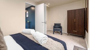 A bedroom with a bed, a chair, and a wardrobe. - Luxury 2BR Corner Apartment I Manchester I City (Greater Manchester)
