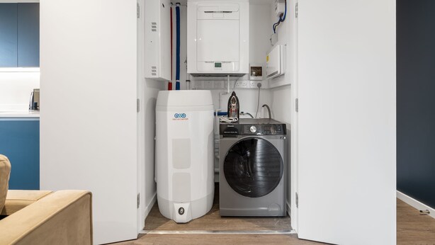 A compact laundry room with a washing machine and a water heater. - Luxury 2BR Corner Apartment I Manchester I City (Greater Manchester)