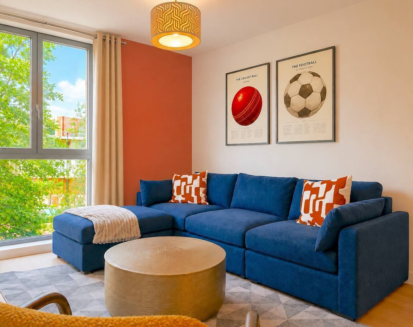 Ein modernes Wohnzimmer mit einem Ecksofa, einem runden Hocker und zwei gerahmten Sportmemorabilien an der Wand.