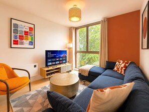 A modern living room with a television, sofa, armchair, and a framed picture on the wall. - Luxury 1-Apt Old Trafford King Bed (Manchester)
