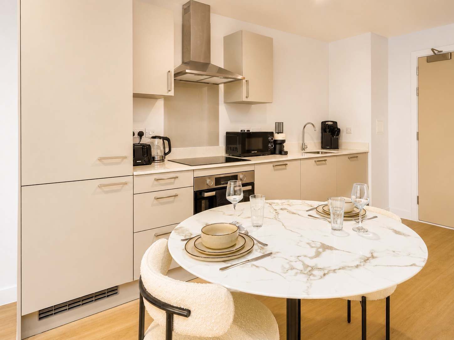 A modern kitchen with a round marble table, built-in appliances, and a compact layout.