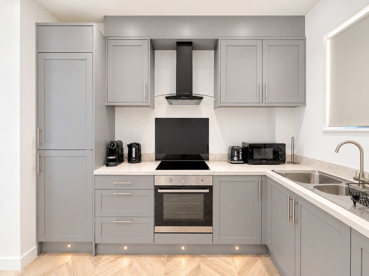 Una cocina moderna con gabinetes grises, una estufa negra, un microondas y un lavamanos.