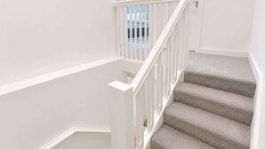 A staircase with white railings and carpeted steps leading to a room with a window. - Beautiful House 2BR - Sleeps 6 - Free Parking - Huddersfield (Huddersfield)