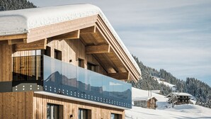 A wooden chalet with a glass balcony, set against a snowy mountain backdrop. - Hotel Bergkristall Zillertal-Adults Only (Hippach)