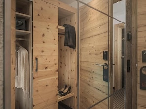 Interior de madera con un vidrio que da a la zona de la ducha, un perchero y un estante con zapatos.