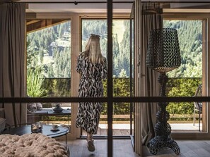A room with a large window, a patterned floor, and a table with a candle. - Hotel Bergkristall Zillertal - Adults Only - Ski-in/Ski-out (Hippach)