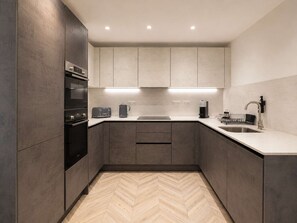 Eine moderne Küche mit integrierten Geräten, einem Fischgrätparkett und einem minimalistischen Design.