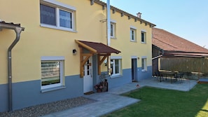 A residential building with a sloped roof, a covered porch, and a small patio area with outdoor furniture. - New, incredibly cozy vacation home in an old barn, near Lake Ellertshäuser (Schonungen)