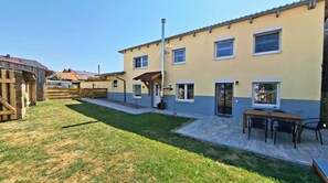 A two-story residential building with a patio area and a small outdoor seating space.