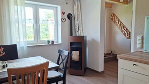 Una habitación acogedora con una mesa de comedor, sillas, chimenea, una ventana con cortinas y un letrero en la pared.