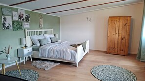 A bedroom with a bed, bedside table, lamp, decorative wall art, and a wardrobe.