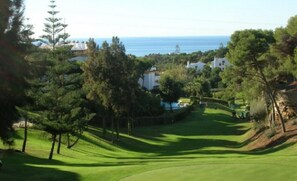 Un parcours de golf offrant une vue sur la mer et sur des maisons situées au loin.