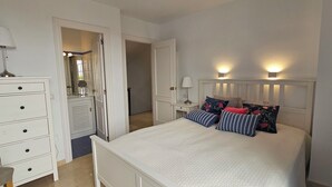 Een slaapkamer met een bed, nachtkastjes, een dressoir en een spiegel.