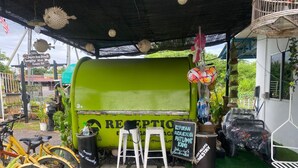 A green food truck with a sign that reads 'RECEPTION' and a chalkboard with text. There are bicycles parked in front and a white stool. - Hotel O Panggas Village Homestay (Kangar)