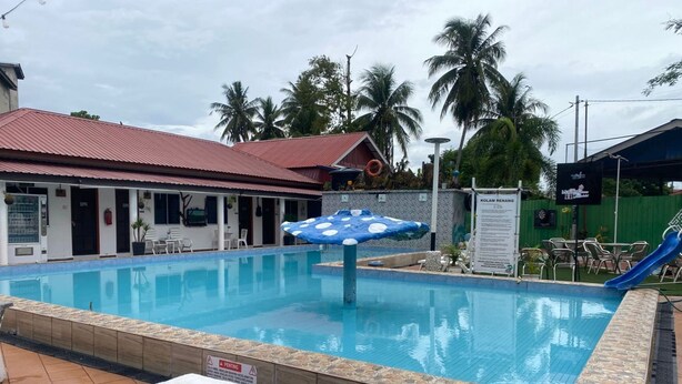 A swimming pool with a tiled deck area, a covered seating area, and a slide. - Hotel O Panggas Village Homestay (Kangar)