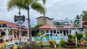 A hotel with a swimming pool, palm trees, and a signboard. - Hotel O Panggas Village Homestay (Kangar)
