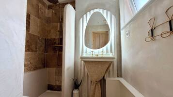 Ein Badezimmer mit Dusche, Waschbecken und Spiegel.