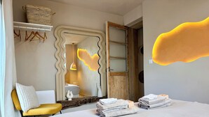 Ein Schlafzimmer mit Bett, Stuhl, Spiegel und Tür.