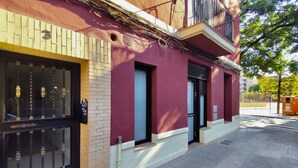 A building with a red facade, a black gate, and a small balcony.