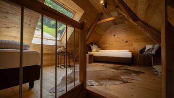 Ein gemütliches Schlafzimmer im Dachgeschoss mit schrägen Wänden, einem Bett, einem Sessel und einem kleinen Tisch.