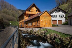 A wooden building with a balcony, a sign reading 'SCHWARZWALD CHALET,' and a stream in front. - Schwarzwald Chalet -Wilde Rench- “Turmfalke“ (Bad Peterstal-Griesbach)