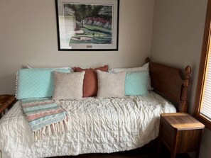 Una cama con cabecera de madera, varios almohadones y una manta.