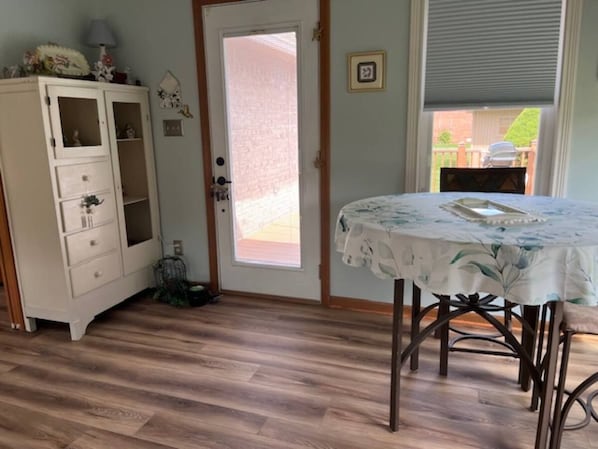 Una habitación con una mesa de comedor, un armario blanco y una puerta que da al exterior.