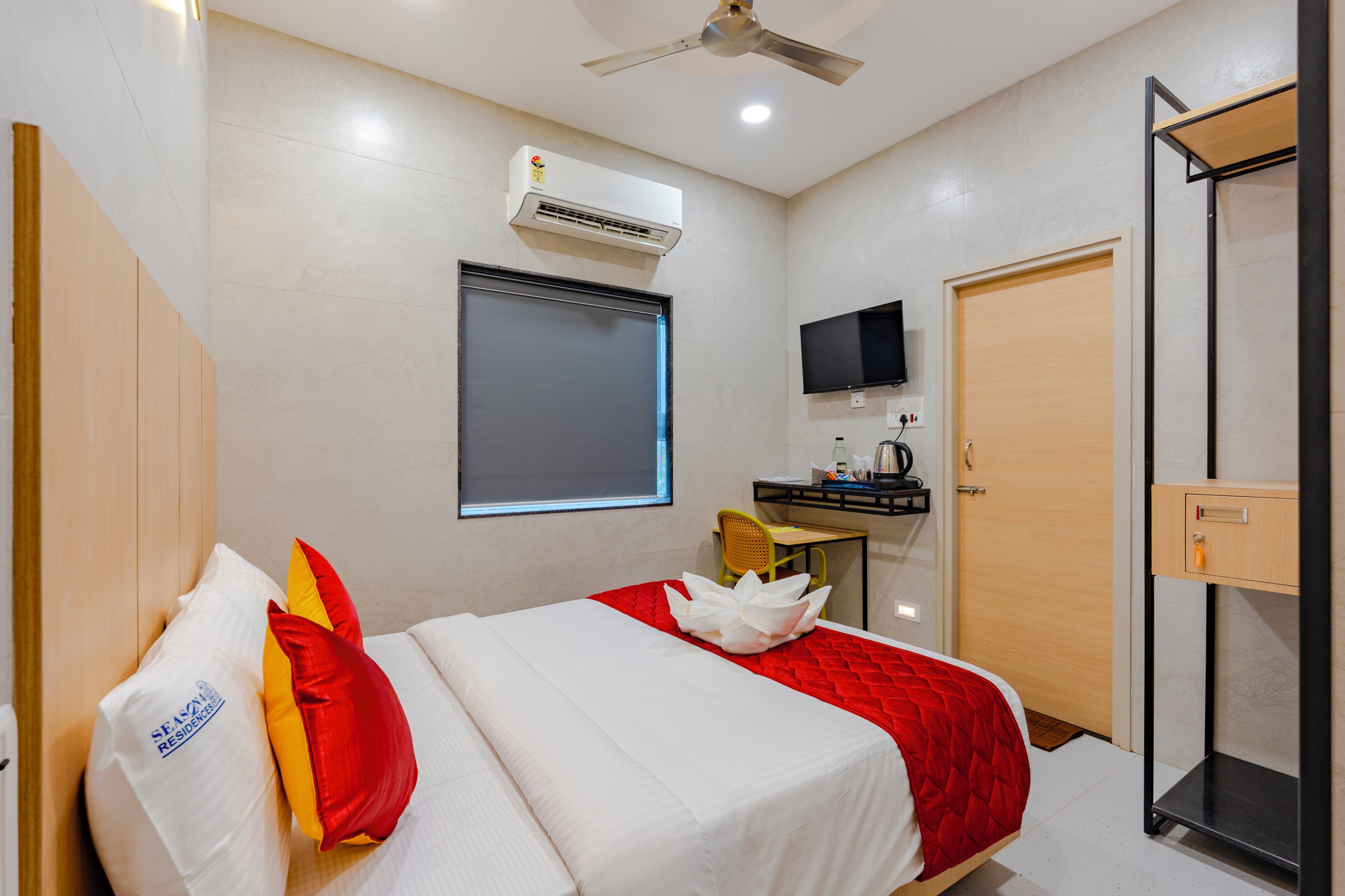Una habitación de hotel con cama, escritorio, silla, televisor y armario.