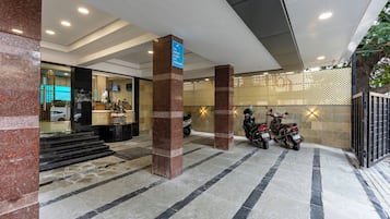 Entrada de un hotel con una recepción, una estatua y dos scooters estacionados.